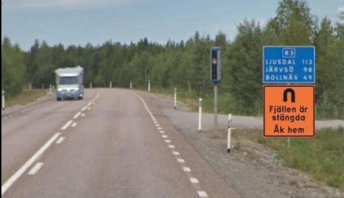 En väg med en skylt som visar avstånd till Ljusdal, Järvsö och Bollnäs. En orange skylt säger "Fjällen är stängda, Åk hem". En husbil ses på vägen.