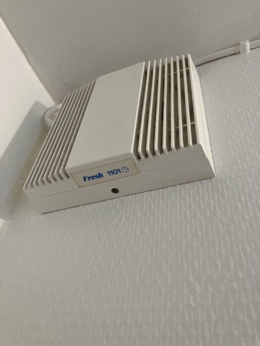 Vit väggmonterad ventilationsfläkt av märket "Fresh 1101", utan synliga inställningskontroller, fotograferad från sidan.