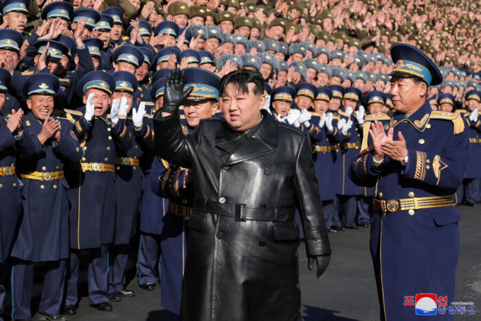 Militär parad med män i uniform, en person i läderrock hälsar.