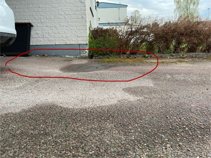 Sänka i asfalten på en uppfart med en spricka där vatten samlas. Röda linjer markerar området.