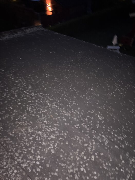 Tak med papptäckning i skymningsljus, med vita fläckar; del av renoveringsprojekt i uterum.