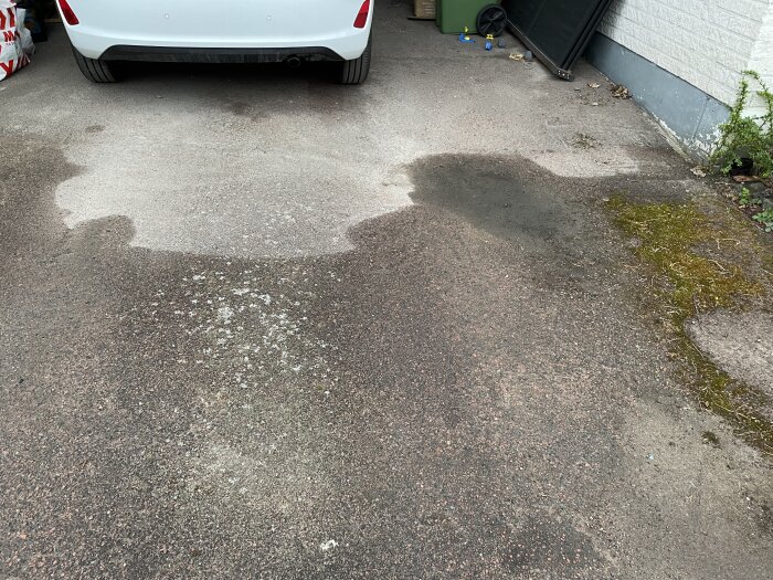 Bilparkeringsplats med en grund grop i asfalten som ser djupare ut i verkligheten, med en vit bil och grön soptunna i bakgrunden.