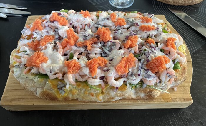 Pinsa med räkor, rödlök, gräddfil, rom och sallad på en träbricka, serverad som långfredagsmåltid.
