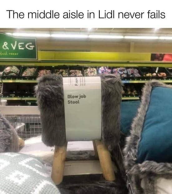 Grå pälliknande pall med texten "Blow job Stool" på ett hyllplan i en butik.
