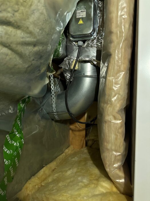 Vägg med isoleringsmaterial och rör, elbox och kablar, diskussion om håltagning och hållare.