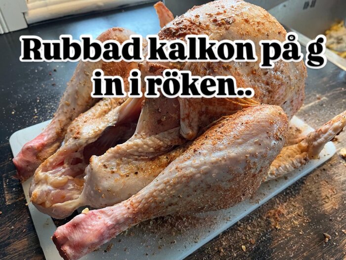 Kryddad rå kalkon redo för rökning på en skärbräda med texten "Rubbad kalkon på g in i röken".