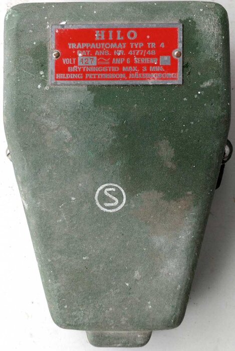 Äldre trappautomat modell MÄ, grön färg med röd skylt som visar specifikationer som 127 volt och 6 ampere.
