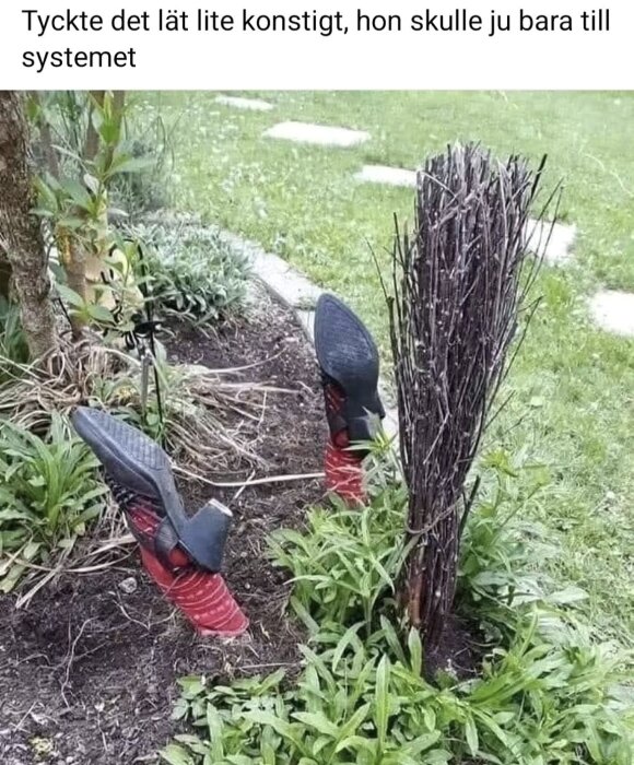 En kvast i en trädgård med höga klackskor placerade upp och ner i marken bredvid.