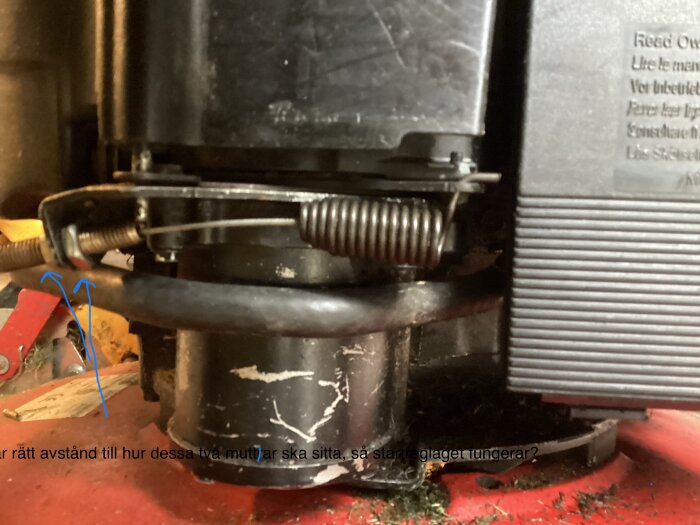 Montering av startreglage med två fjädrar och muttrar på en motor, blå pilar visar positioneringsproblem.