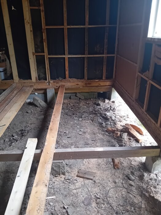 Träramar och golvreglar i ett pågående byggprojekt, med exponerade reglar och brädor i en ofärdig väggkonstruktion.