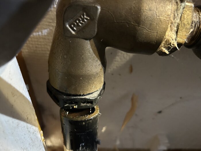 Vinkelkoppling i metall ansluten till ett rör i ett byggprojekt.