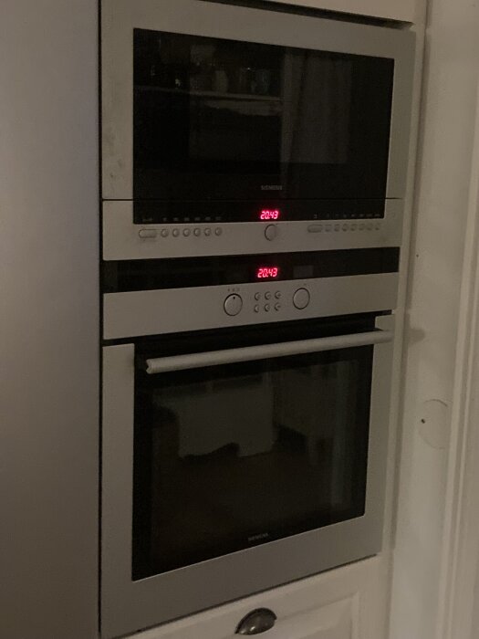 Inbyggd ugn och mikrovågsugn i ett köksskåp, med frågor om ventilation och installation.