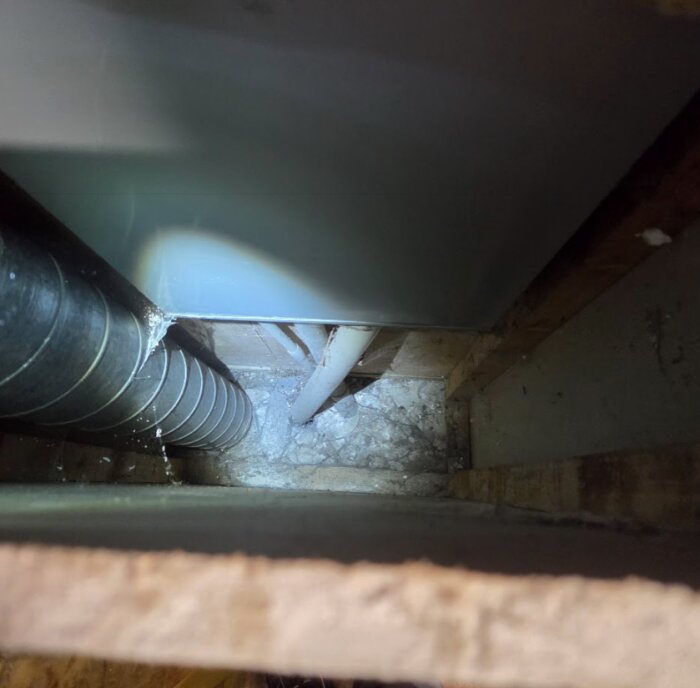 Rör och en väggyta i ett trångt utrymme, där det vänstra röret är inkommande till ett skåp enligt inlägget.