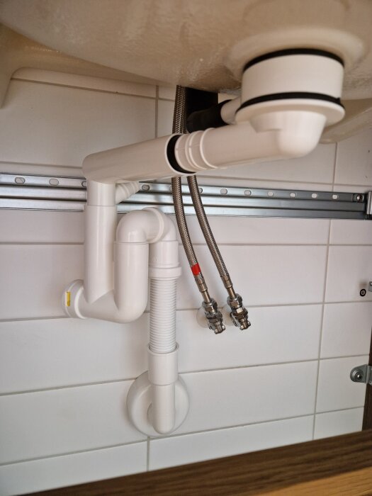 Under-sink plumbing with pipes and hoses possibly causing overflow issues when using soapy water.