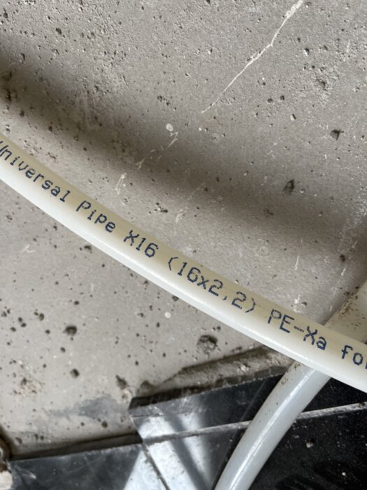 PEX-rör med texten "Universal Pipe X16 (16x2.2) PE-Xa" mot en betongvägg.