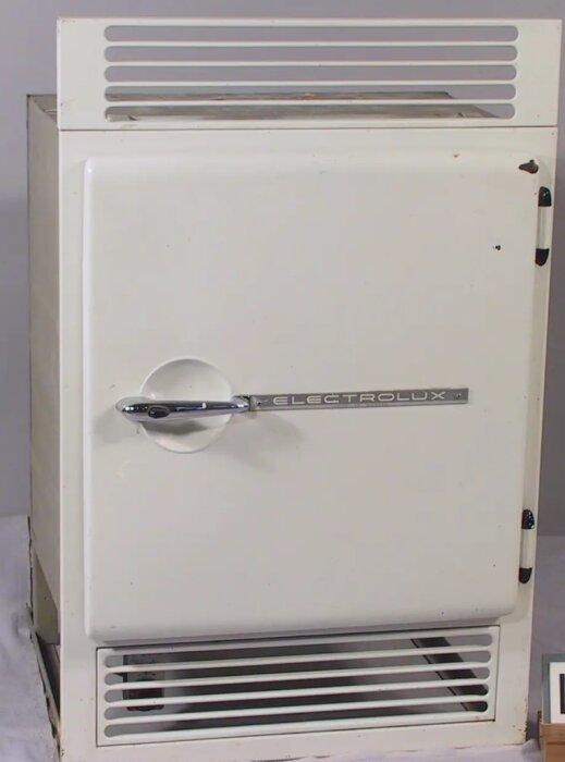 Gammalt vitmålat Electrolux-absorptionsskåp från sommarstuga, med ventilationsöppningar och handtag.