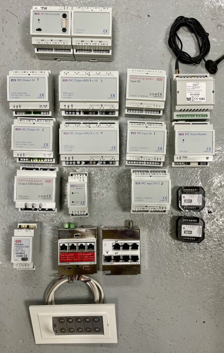 Olika komponenter för smart husstyrning inklusive IHC Visual Controller, IHC Input och Output moduler samt IHC dimmer och LexCom moduler.