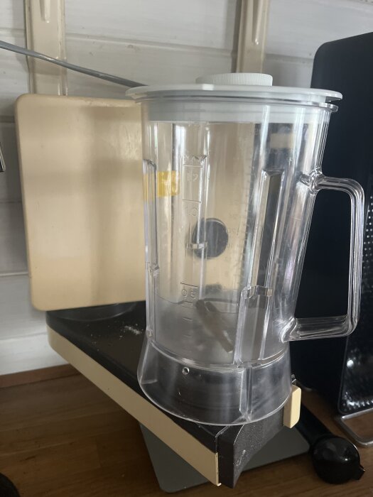 Plastmixer på en gammal vägghängd basenhet i kök med vit bakgrund.