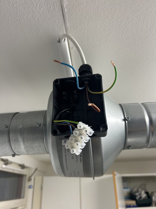 Kopplingsbox med exponerade ledningar nära ventilationskanal i taket.