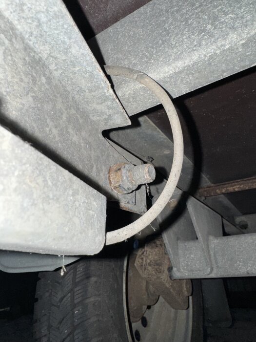 Närbild av rostig bult på Tiki cs265-r släpvagn, fast vid tippfunktionen, med en metalltråd synlig vid sidan.
