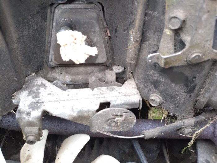 Bränsleläcka från förgasare och aktiverad choke på motor; bild visar detalj av förgasarens konstruktion och mekanik med synliga delar och skruvar.