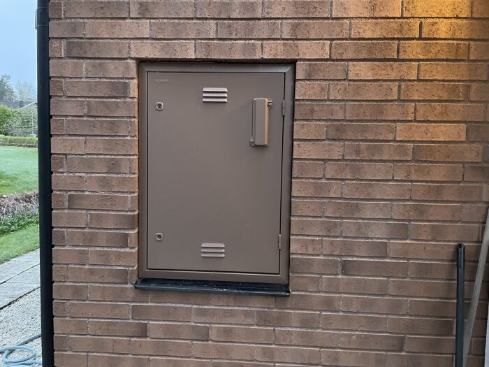 Inbyggt mätarskåp i en tegelfasad, potentiell plats för laddbox till höger.