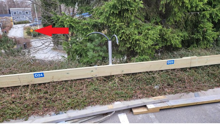 Trädgård med träd och en handgjord träbarriär, hastighetsskylt i bakgrunden med 5 km/h, röd pil pekar på skylten.