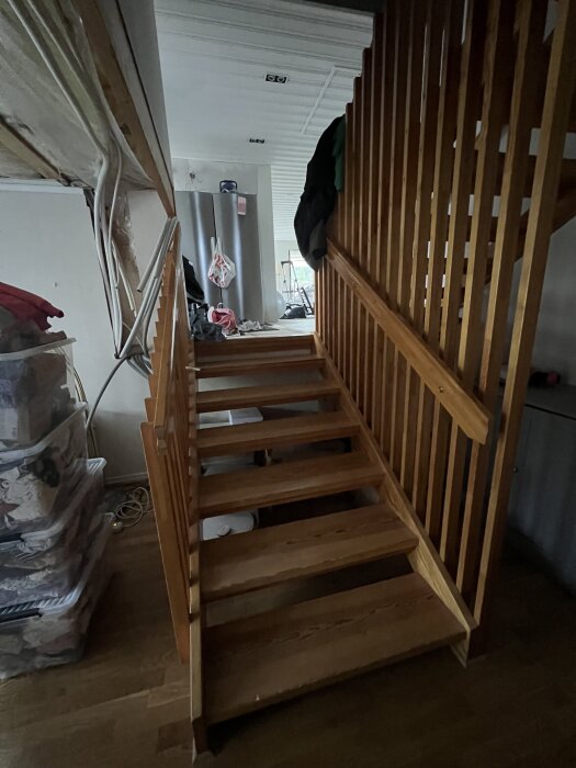 Furutrappa med sju steg och ledstång, parkettgolv och väggfast räcke, halvplan synligt vid renovering av äldre byggprojekt.