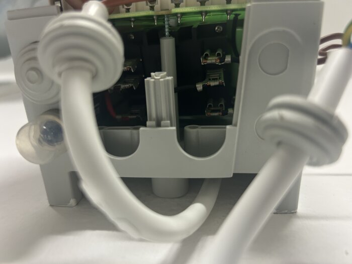 Elektrisk komponent med kretskort och kablar, föreställer baksidan innan kretskortet skruvats fast.