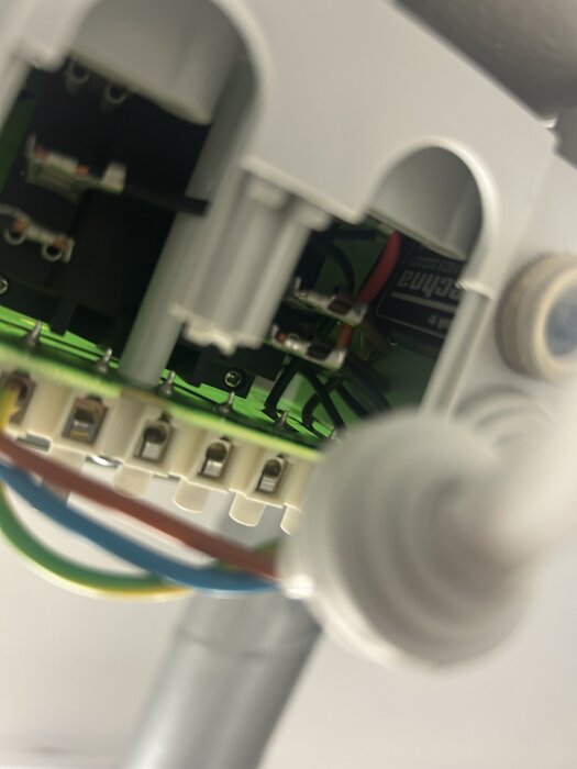 Kretskort med anslutna kablar innan fastskruvning, närbild på elektroniska komponenter och ledningar inuti en enhet.