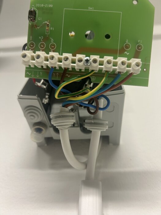 Kretskort med kablar kopplade till anslutningar, inklusive jordning, inuti en elektrisk box.