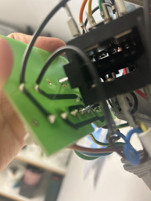 Elektroniskt kretskort med kablar i olika färger, sedd från en vinkel där komponenterna är delvis skymda.