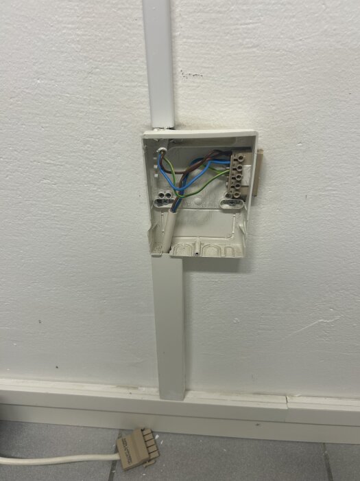 Öppen elcentral i vägg med synliga kablar för koppling mellan trafo och fläkt.