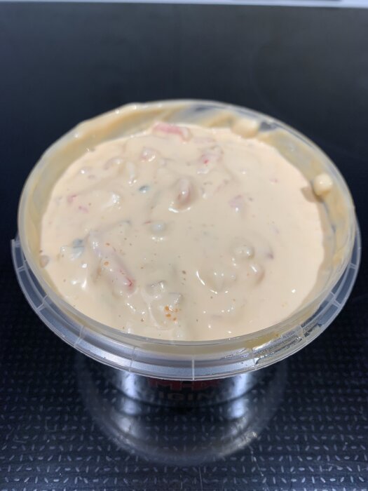 Öppen plastburk med korv och räksallad redo att serveras.