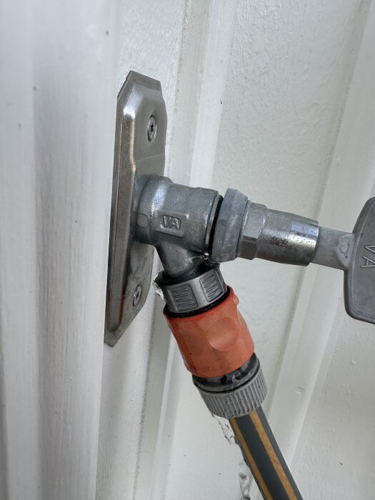 Vattenutkastare läcker när trädgårdsslang är ansluten, visar vattenflöde från utkastaren snarare än från slangkopplingen.