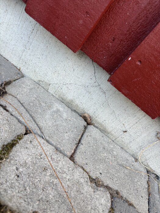 Spricka i kantelement på husgrund byggd 2005, med rödmålad träpanel ovanför och betongplattor nedanför.