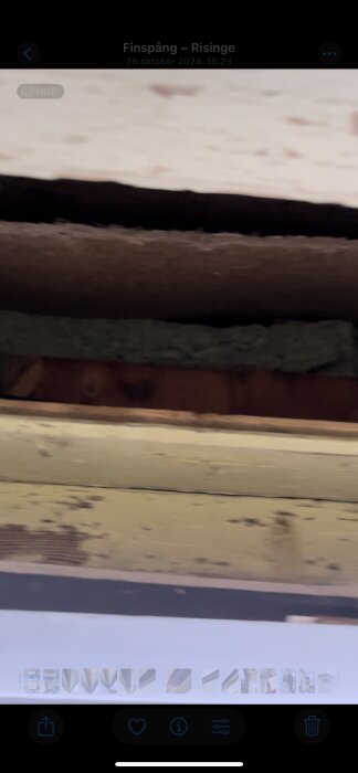 Isolering synlig genom takfotens ventilationshål, med masonit och läkt synliga, installation med plastskikt längst ner i hörnet.