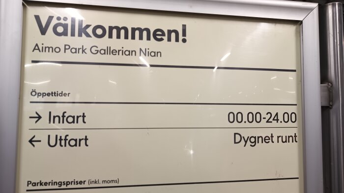 Skylt vid Aimo Park i Gallerian Nian med öppettider för infart 00.00-24.00 och utfart dygnet runt. Parkeringspriser inkl. moms nämns också.
