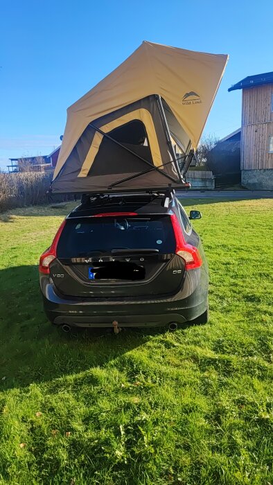Bil med utfälld taktält på gräsmatta under klarblå himmel, redo för test hos barnbarnen.