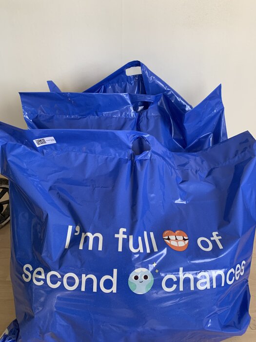 Blå påsar med texten "I'm full of second chances" och emojis av mun och jord, placerade mot en neutral bakgrund.
