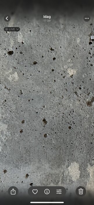 Närbild av en ojämn betongyta med små hål och fläckar, som diskuterats för att jämföra synligheten av betongens yta.