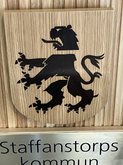 Staffanstorps kommunvapen i ek, med skånsk grip rökt med ammoniak. Detaljerad träfiberriktning på olika kroppsdelar.