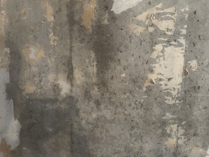 Vägg med avskalad färg och fläckar, resultat efter tvättning med vatten och diskmedel.