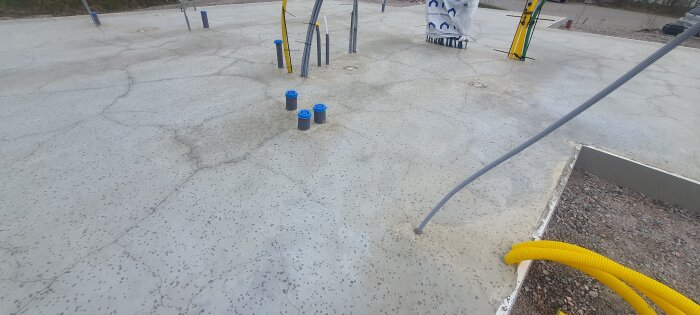 Betongplatta med flera sprickor och rörgenomföringar synliga. Plattan visar tecken på torksprickor och saknar avslutande ytskikt.