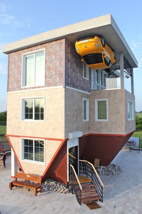 Omvänt hus med bilen upp och ner på taket.