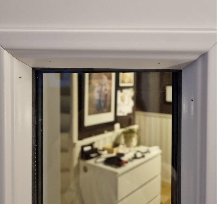 Nyinstallerat sidoglas med synlig lutning, inifrån sett. Bakom glaset syns en vit byrå och tavlor på en skiffergrå vägg.