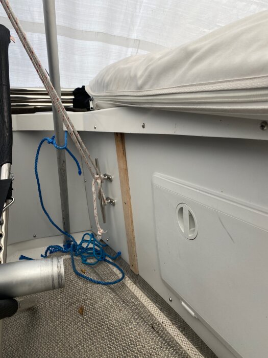 Bänk och repinstallation i en båt, med vit dyna och blått rep, del av projekt för ombyggnad av Bertram 28 Flybridge Cruiser.