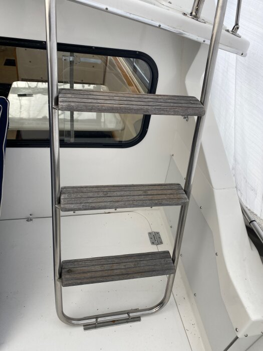 Trappa i rostfritt stål med teaksteg som leder upp till flybridge på en båt.