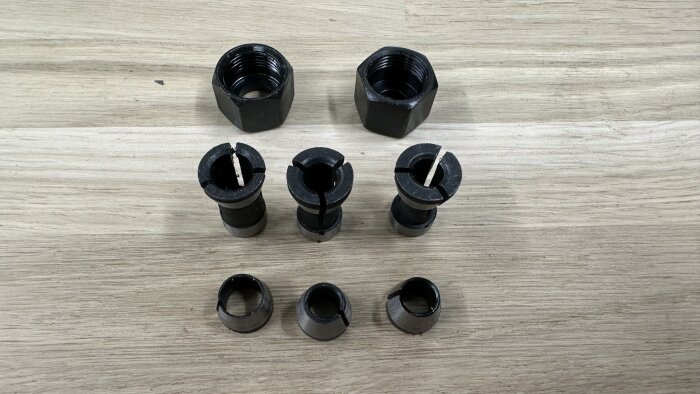 Svart hylssats med tre öppna och två kompletta hylsor placerade på ett ljust trägolv, avsedd för maskinarbete och mätning.