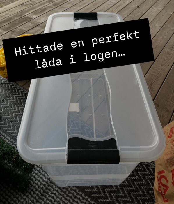 Plastlåda med lock för förvaring av toalettpapper, står på ett trägolv. Texten "Hittade en perfekt låda i logen..." syns på bilden.